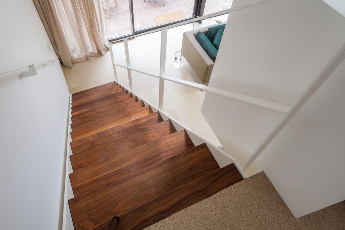 Rechte trap met witte trapleuning en donkere treden in woonkamer